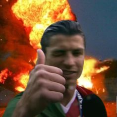 a man giving the thumbs up in front of a large explosion