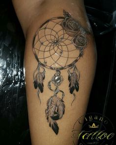 a woman's thigh with a dream catcher tattoo design on her leg and roses