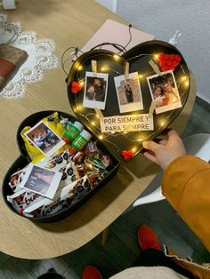 someone is holding a heart shaped box with pictures on it and lights in the shape of a heart