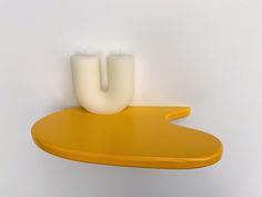 a yellow shelf with two white vases on it