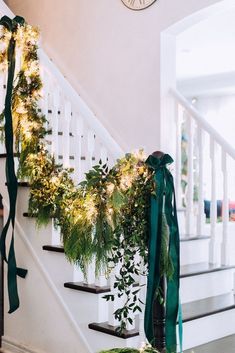 the stairs are decorated with greenery and garlands for holiday decor, along with a clock on the wall