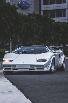 a white sports car parked on the side of a road next to a tall building