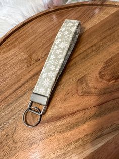 a keychain on top of a wooden table with a white flowered design