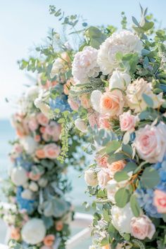 an outdoor wedding ceremony with flowers and greenery on the aisle at the beach in front of the ocean