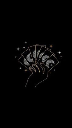 a hand holding four cards with the moon and stars above it on a black background