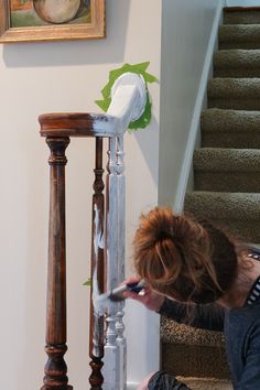 a woman kneeling down on the ground next to a stair case with an object in front of her