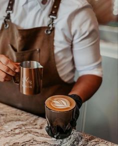 a person with an apron holding a coffee cup