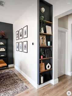 a living room filled with furniture next to a wall mounted bookshelf on a wooden floor