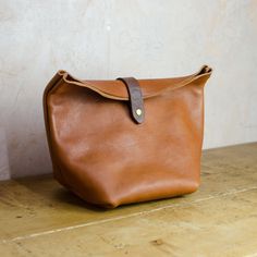 Experience the elegance of our uniquely designed accessory bag, crafted from Italian full grain leather in Dark Tan. Finished with dark brown vegetable-tanned leather clasp with an antique brass press stud, this bag combines style and functionality. Its generous capacity is perfect for all your travel toiletries, and it can also hold your keys, phone, wallet, makeup, and more! Designed with durability and simplicity in mind, this classic yet modern bag is made to stand the test of time. Approx D Classic Brown Pouch Saddle Bag, Classic Brown Saddle Bag Pouch, Brown Leather Handle Pouch For Everyday Use, Everyday Brown Pouch With Leather Handles, Brown Saddle Shoulder Bag With Smooth Grain, Brown Smooth Grain Saddle Shoulder Bag, Classic Leather Pouch With Soft Leather, Classic Brown Pouch With Leather Lining, Brown Leather Pouch With Smooth Grain