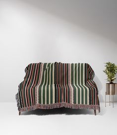 a green and red striped couch next to a potted plant