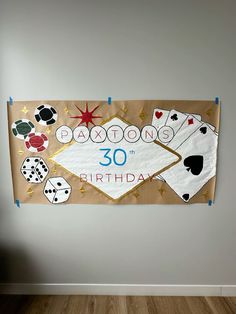 a birthday banner hanging on the wall with playing cards and dices in front of it