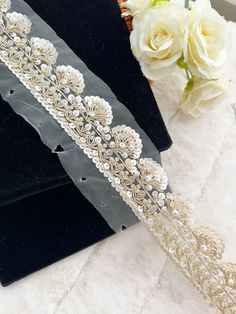 two wedding garters on display next to white flowers and black velvet envelopes