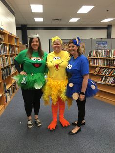 three women in costumes are posing for the camera while standing next to bookshelves