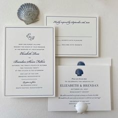 the wedding stationery is laid out on top of each other, along with a seashell