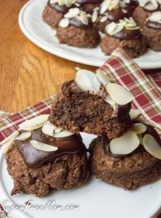 two white plates topped with cupcakes covered in chocolate frosting and almonds