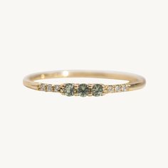 a gold ring with three green stones on the top and two white diamonds on the bottom