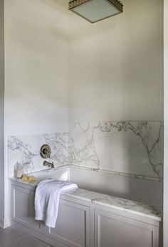 a bathroom with marble walls and white cabinets