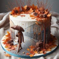 a cake decorated with autumn leaves and an image of a person walking in the rain