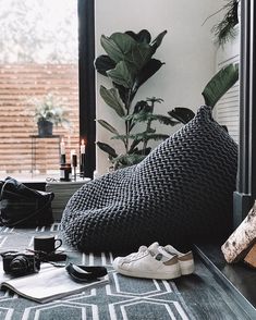 a black and white photo of shoes on a table next to a window with plants in the background