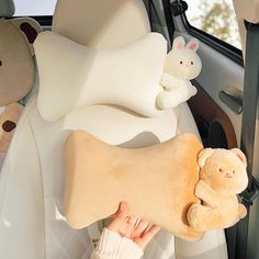 a person holding a stuffed animal in the back seat of a car with other stuffed animals