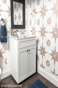 a white sink sitting under a bathroom mirror next to a blue rug on top of a wooden floor