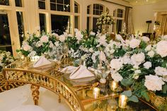 there is a table with flowers on it and gold plates in front of the tables