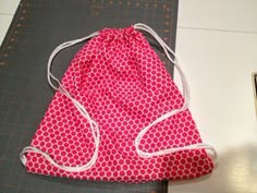 a pink and white bag sitting on top of a cutting board next to a pair of scissors