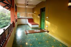 a room with green and yellow walls has a swing in the middle, two benches on either side