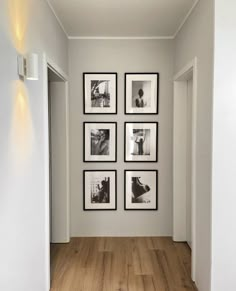 a hallway with white walls and pictures on the wall, along with wooden flooring