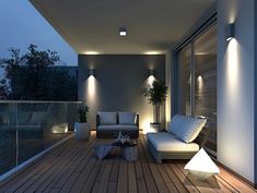 an outdoor living area with couches and lamps on the balcony at night, lit up by lights