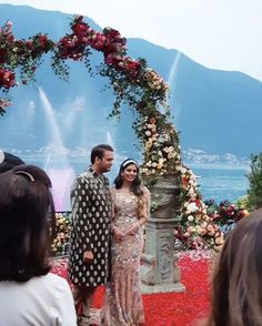 a man and woman standing in front of an arch with flowers on it at a wedding ceremony