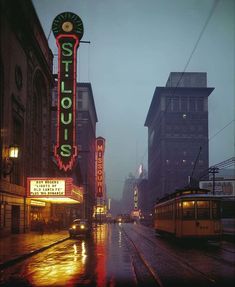 a city street with traffic and neon signs on the side of buildings at night time