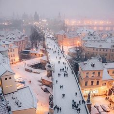 people are walking in the snow near buildings