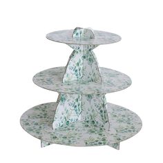 three tiered cake stand with green flowers on the top and bottom, in front of a white background