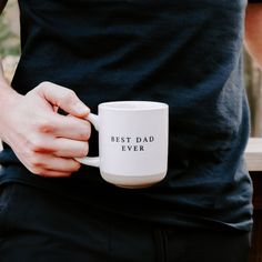 a person holding a coffee mug with the words best dad ever on it in their left hand