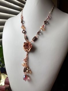 A shimmery handcrafted polymer clay rose is the focal point of this beautiful crystal and copper bead necklace. Delicate peachy pink crystal and champagne colored glass are combined with rose gold plated chain and antiqued copper accents for a piece elegant enough for a bride. This listing comes with matching copper hooked earrings, 2.5 inches long. The necklace fastens with a lobster claw and adjusts between 17 and 21 inches. Bohemian Rose Gold Copper Jewelry, Pink Wire Wrapped Copper Jewelry, Adjustable Pink Copper Jewelry, Rose Gold Beaded Dangle Jewelry, Handmade Rose Gold Dangle Necklaces, Rose Gold Copper Wire Wrapped Necklaces, Adjustable Rose Gold Necklaces With Rose Design, Adjustable Rose Gold Necklace With Rose Design, Handmade Rose Gold Copper Necklace