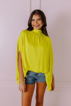 - Get in a chic state of mind with this trendy top! - Unlined lightweight material with a satin finish - A mock neckline with back tie closure and a keyhole detail - Draped half sleeves - An oversized silhouette that ends in an uneven hemline with a gathered elastic detail in front Chartreuse Shirt Outfit, Relaxed Fit Pre-shrunk Yellow Tops, Yellow Relaxed Fit Pre-shrunk Top, Chartreuse Blouse, Chartreuse Earrings, Trendy Top, Mock Neckline, Oversized Silhouette, State Of Mind