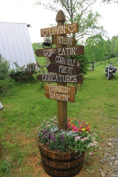 a wooden sign sitting on top of a barrel filled with flowers