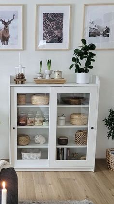 a living room with white furniture and pictures on the wall above it, along with a candle