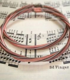 three red cord bracelets sitting on top of sheet music