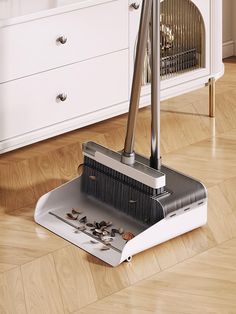 a floor sweeper sitting on top of a hard wood floor next to a cabinet