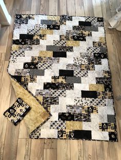 a black and white quilt on the floor next to a pair of pillows in front of it