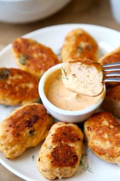 a white plate topped with crab cakes and dipping sauce