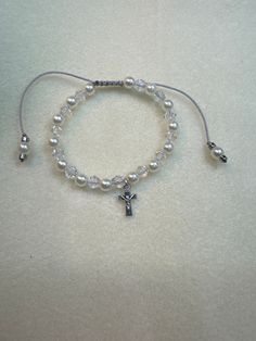 This is a religious pearl and Crystal beaded bracelet, that I made for my granddaughter's First Holy Communion. Intermixed are bicone crystals that make this bracelet sparkle. It has an adjustable macrame slip closure, made with gray eslon cording. In sizes of 6-10 approximately. This bracelet can be made as an elastic stretch bracelet. Bracelet Knots, Crystal Beads Bracelet, First Holy Communion, Holy Communion, White Pearl, Stretch Bracelet, Stretch Bracelets, Clear Crystal, Pearl White