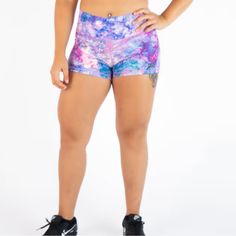 a woman in purple and blue shorts with her hands on her hips, posing for the camera