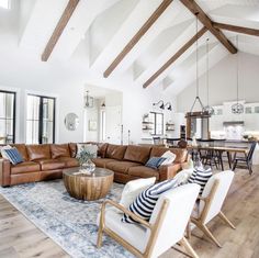 a living room filled with lots of furniture and wooden beams on the ceiling over a large area rug