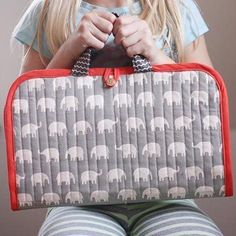 a woman sitting on the floor holding an elephant print purse in front of her face