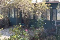 a green house surrounded by trees and bushes