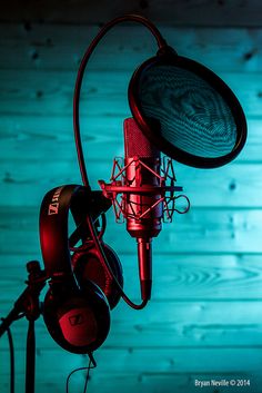 a microphone and headphones are lit up against a wooden wall with blue lights in the background