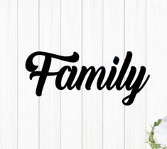 the word family written in black ink on a white wooden background with flowers and greenery